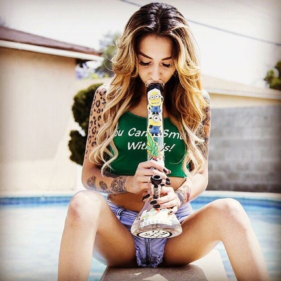 cute girl in crop top smoking weed bong by pool